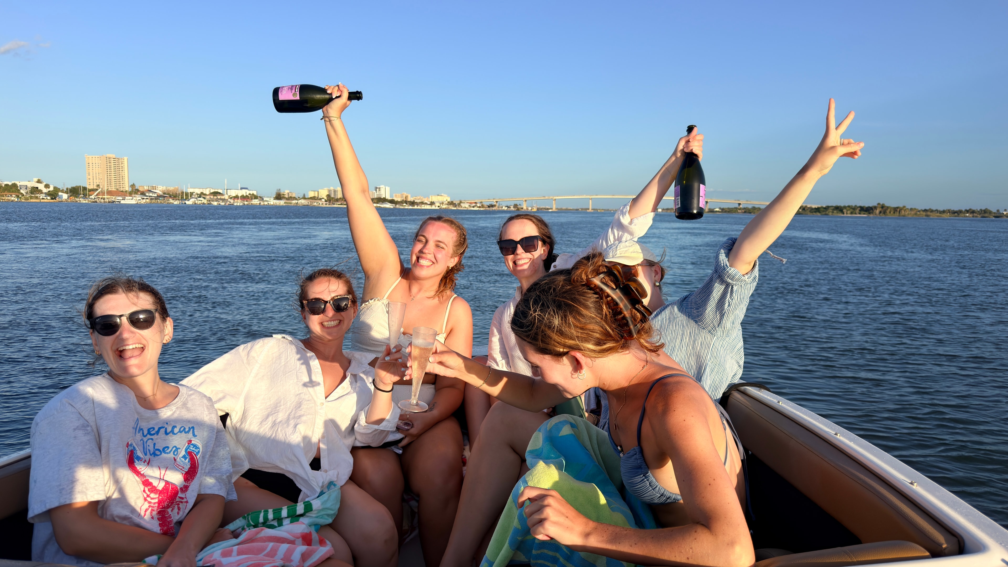 Friends celebrating with champagne aboard a private Florida boat charter with the waterfront skyline behind them